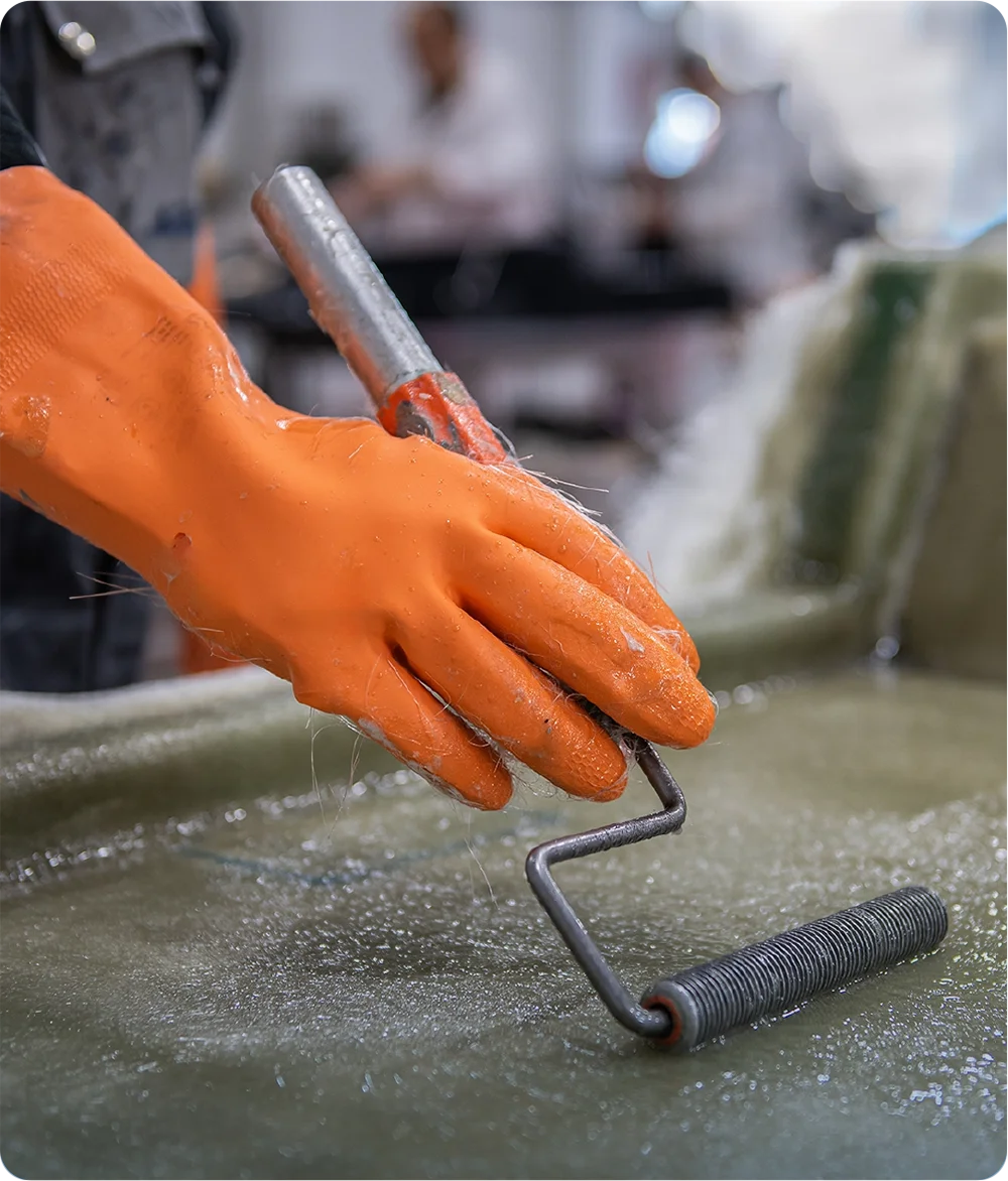 Fiberglass application with a roller on a pool mold at the Fiber factory